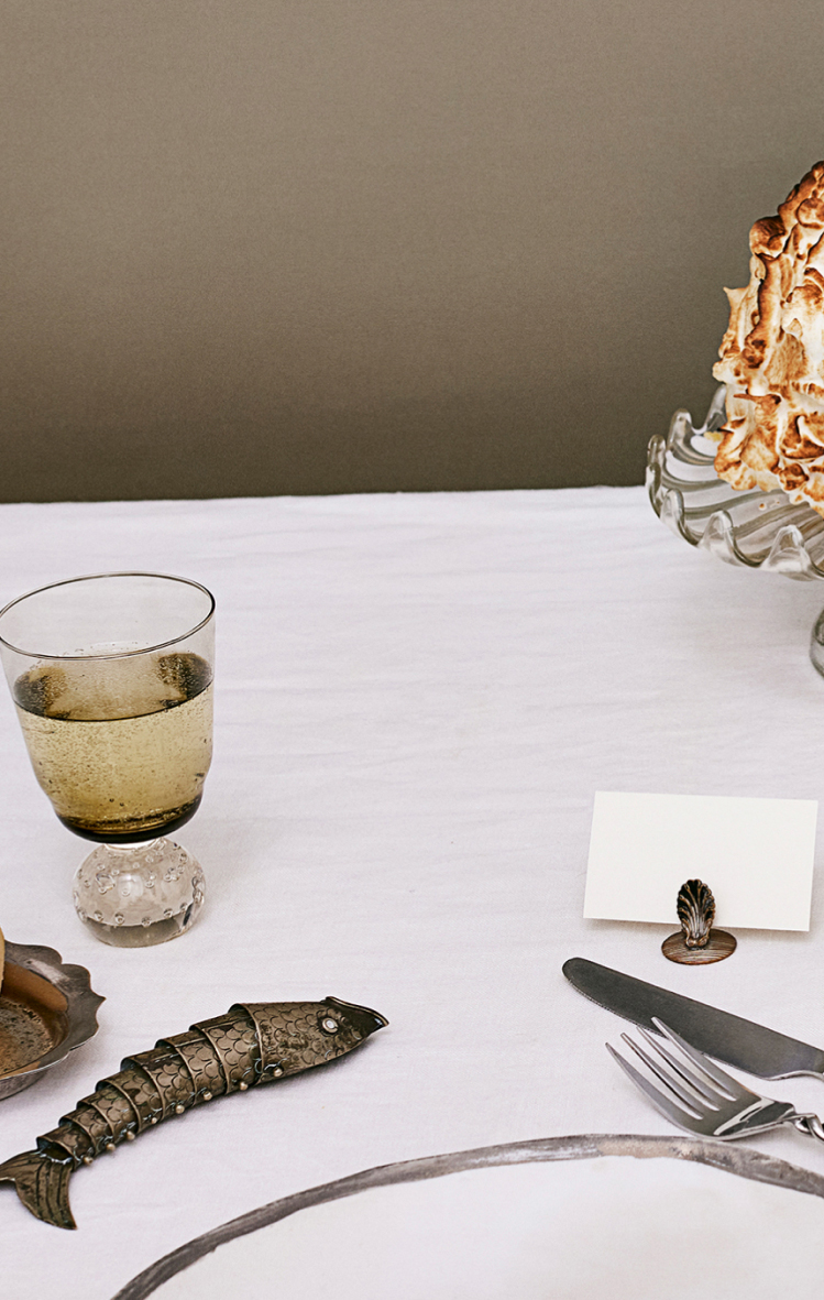 A professional dinner party scene featuring various tableware and food such as a lamp, a poached pear, a baked Alaska, and a seafood tower.