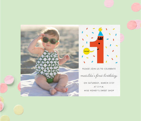 An invitation with a photo of a baby and the number 1 in a party hat.